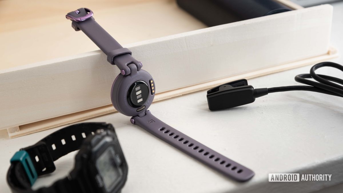 Het Garmin Lily Sport Edition smartwatch naast de eigen oplaadkabel en een Casio-horloge.