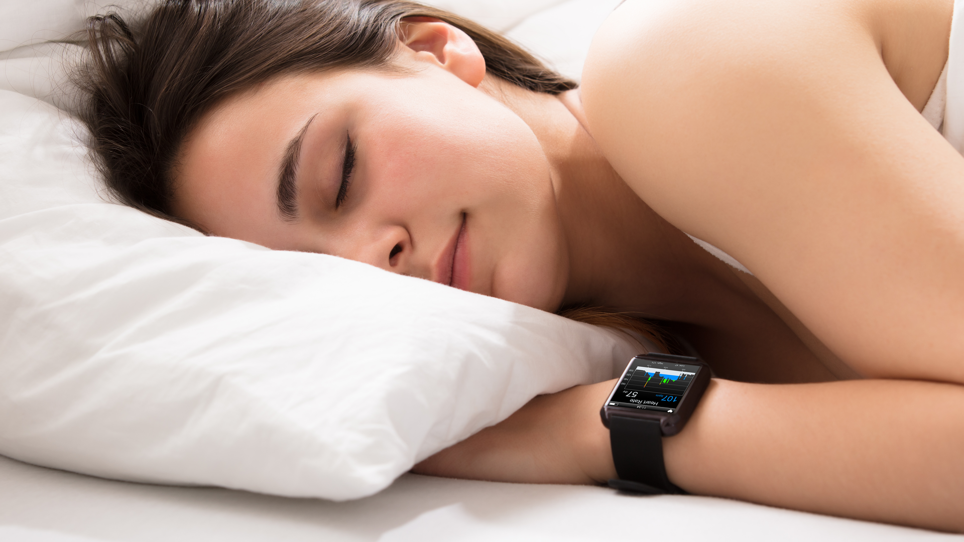Person Sleeping On Bed With Smart Watch Showing Heartbeat Monitor