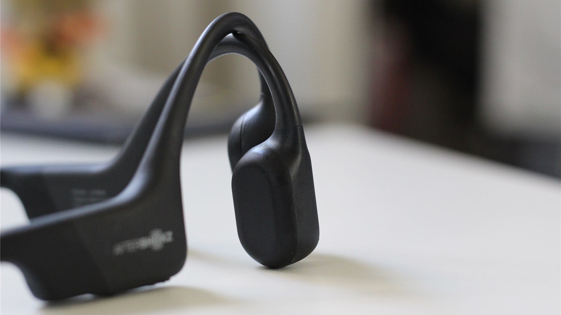 A pair of AfterShokz bone conduction headphones on a table.