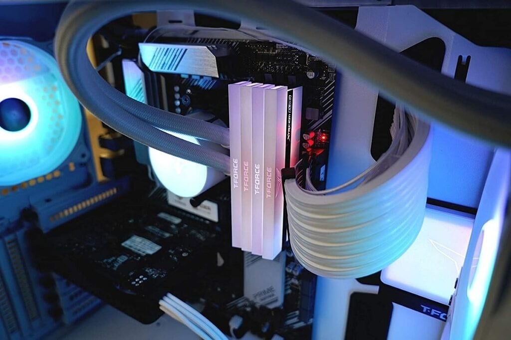 Interior of a gaming PC with RGB lights, coolant tubes, and power connectors.