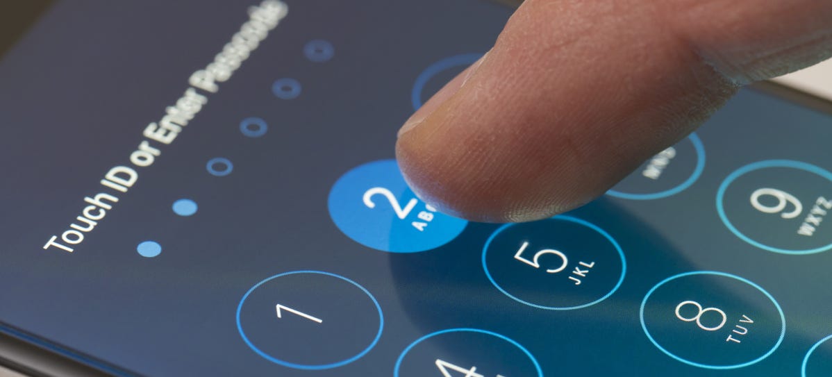 Finger tapping in a passcode on an iPhone screen.