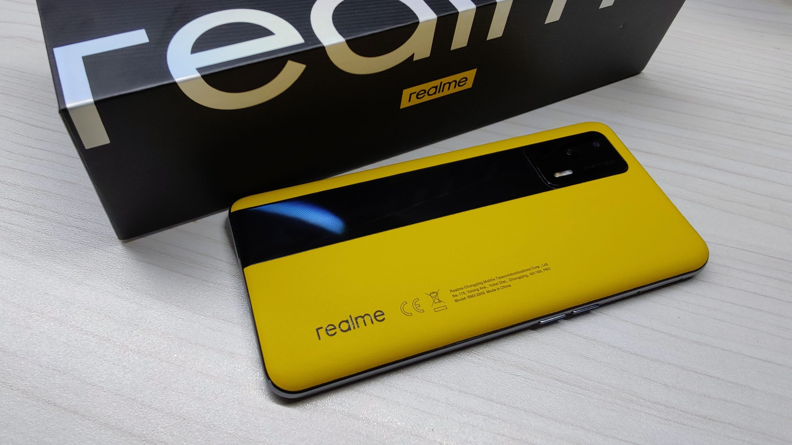 Realme GT Europe in yellow next to the packaging, showing rear of the phone.