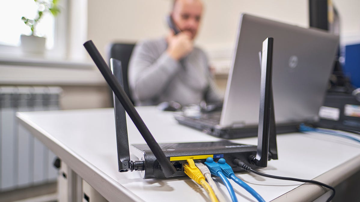 Een persoon die aan een bureau werkt met meerdere apparaten aangesloten op een wifi-router.