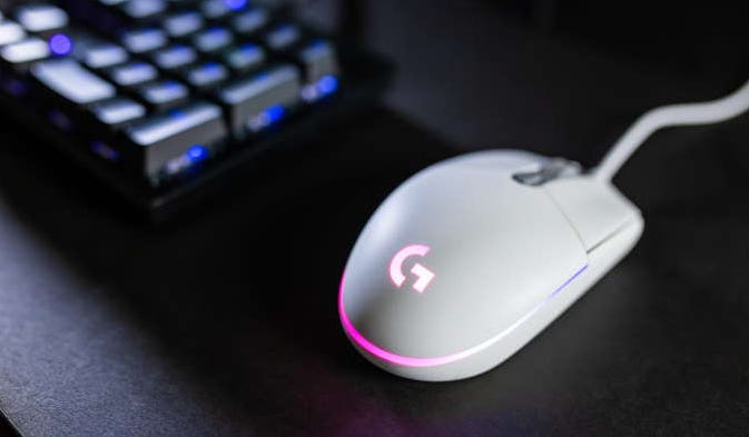white logitech rgb mouse on black dekstop, with keyboard in background