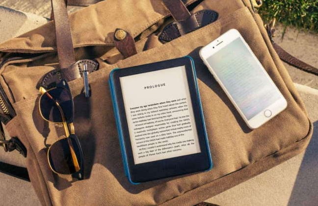 kindle in case on canvas bag with phone and sunglasses