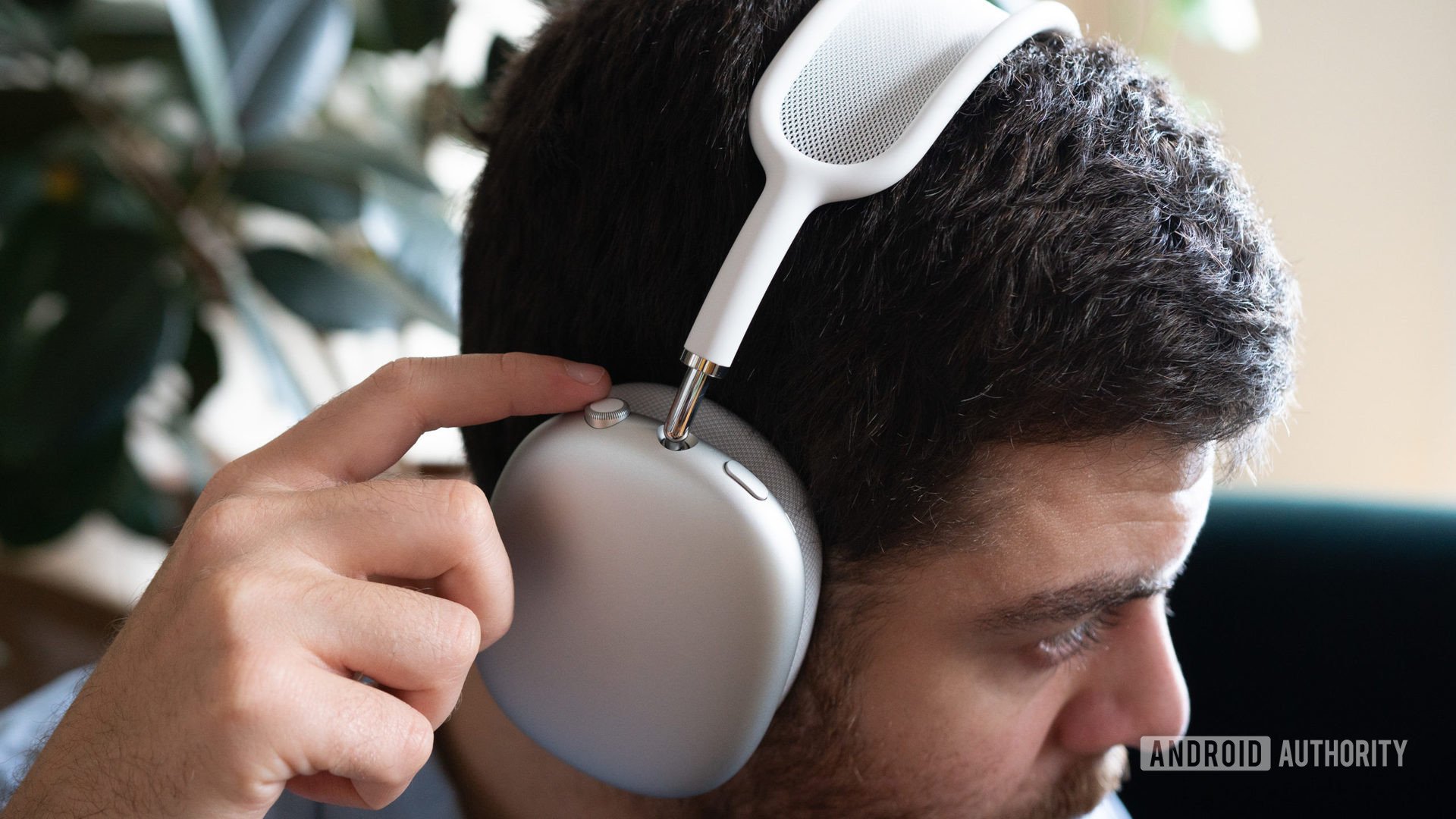 A man wears the Apple AirPods Max and uses the onboard headphone controls.
