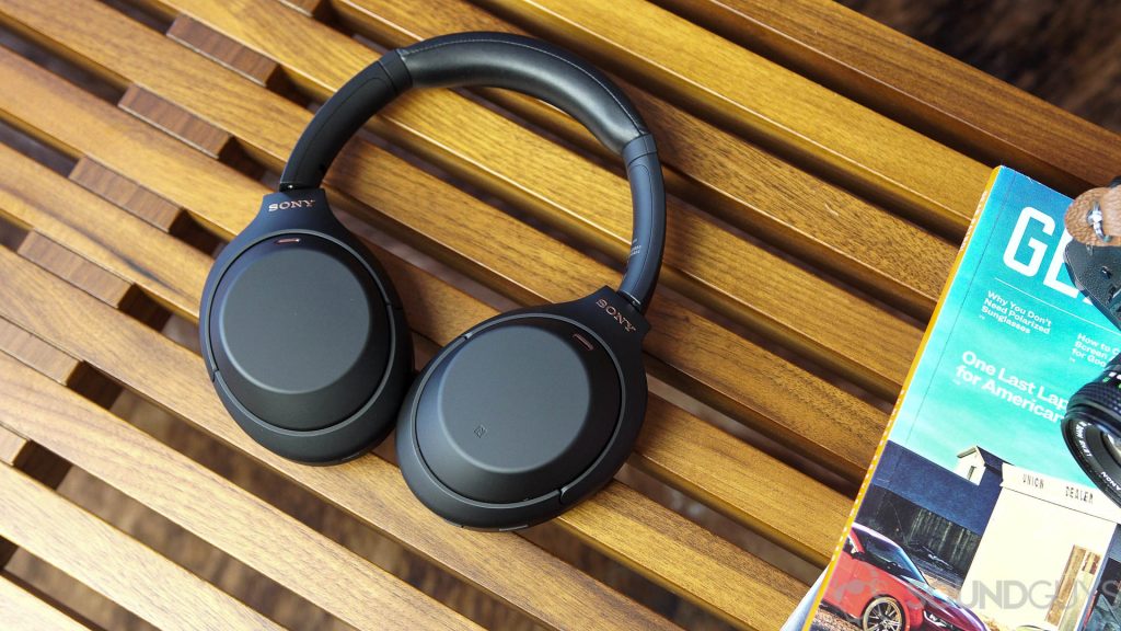 Slušalke Sony WH-1000XM4 poleg revij na leseni klopi