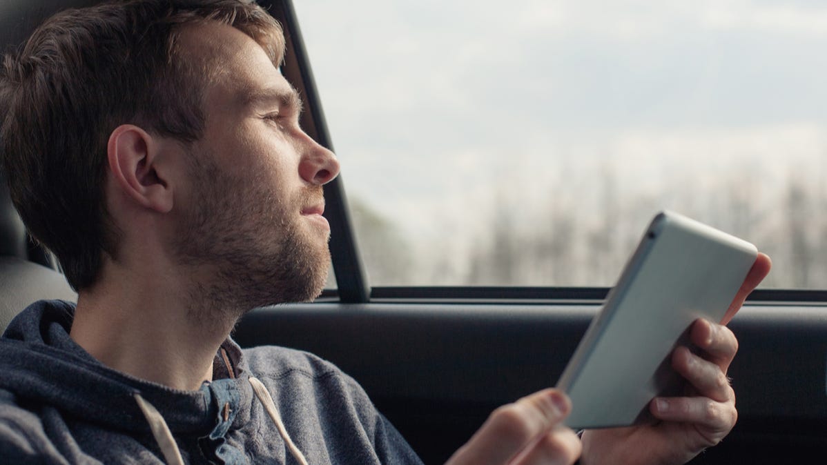 Man in a car using a tablet.