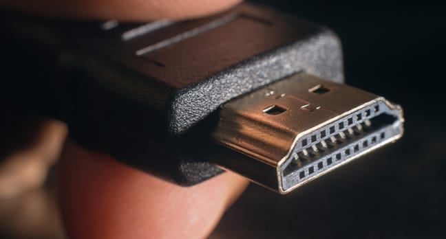 Closeup of an HDMI connector between a person's fingers.