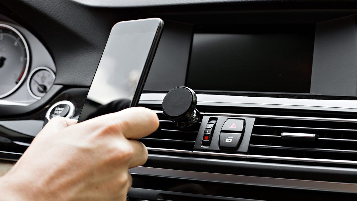 A person docking their phone on a magnetic in-car phone dock.