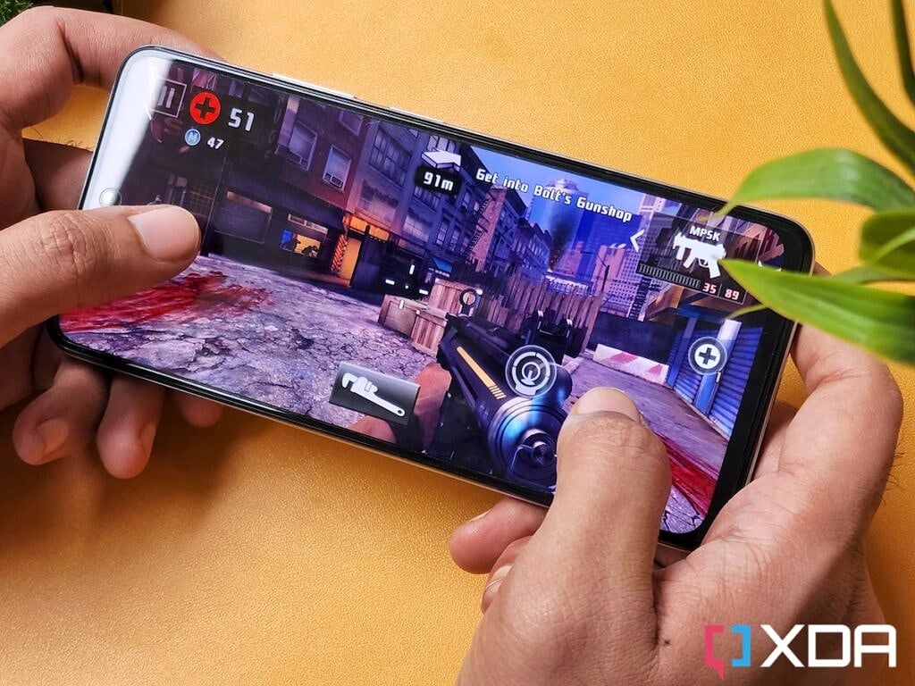A person playing Dead Trigger 2 mobile game on Redmi k50i smartphone