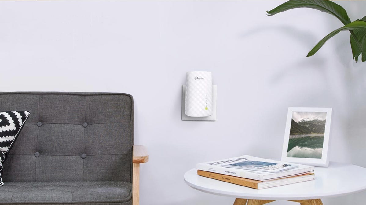A TP-Link extender plugged into the wall of a living room.