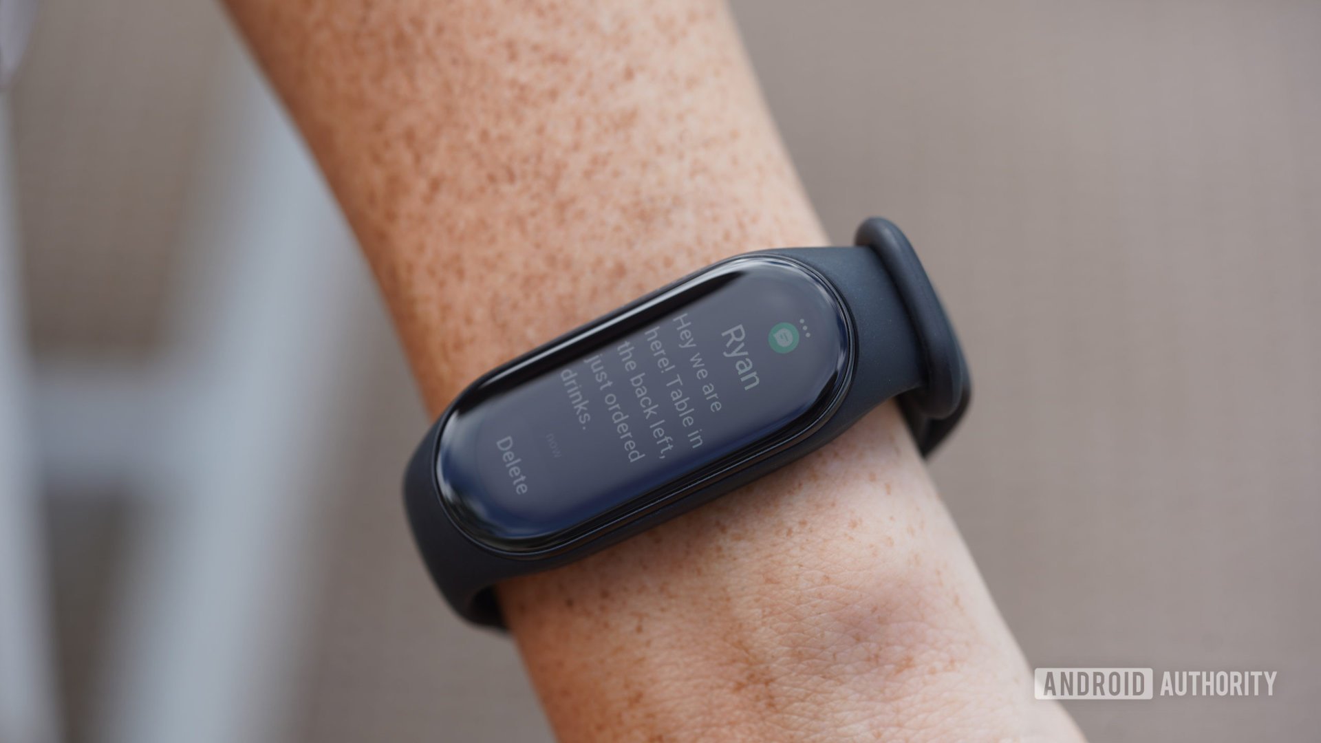 A Xiaomi Mi Band 7 displays a user's text notification on screen.