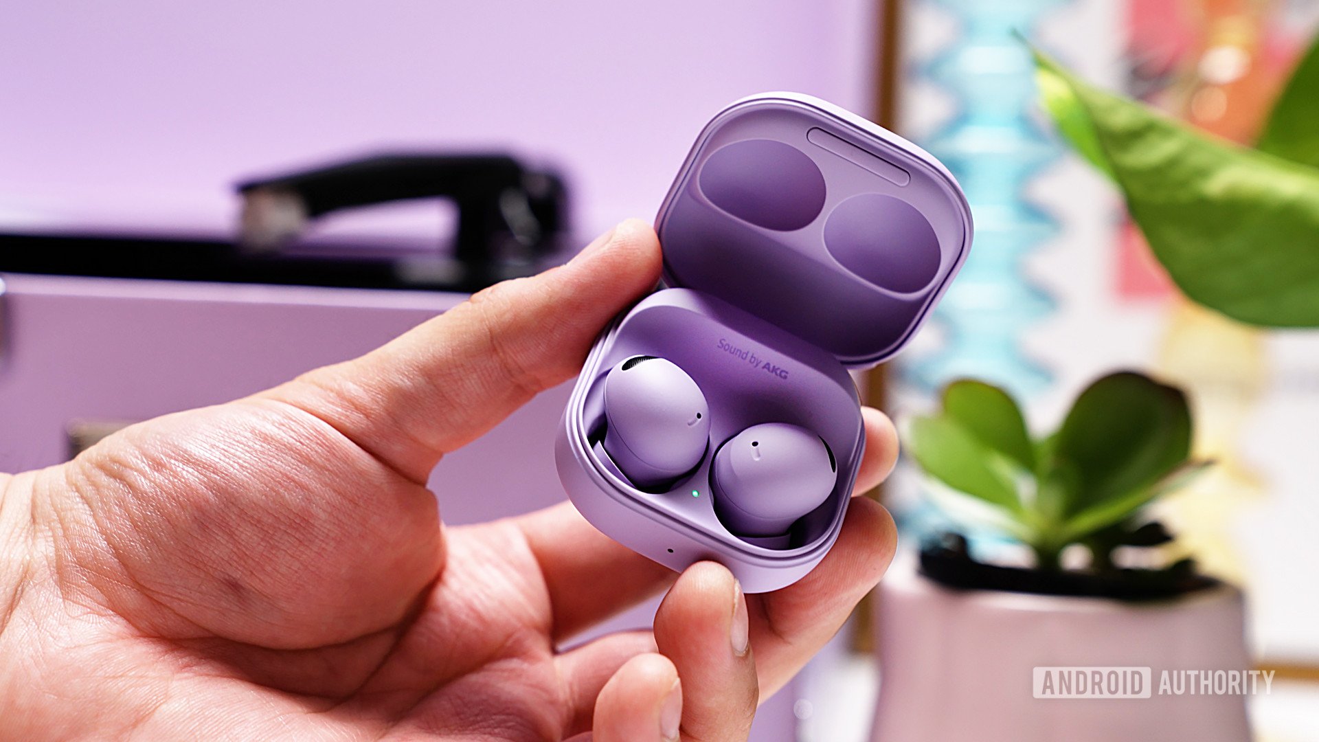 A set of Samsung Galaxy Buds 2 Pro in Bora Purple in their case being held up by a hand.