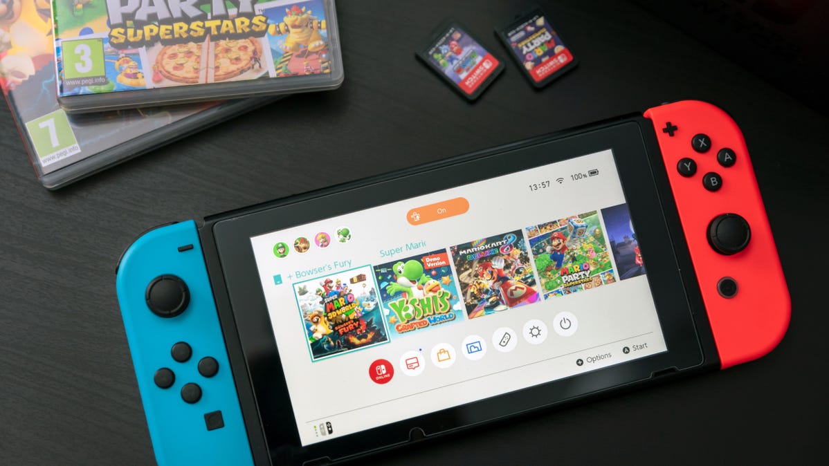 A Nintendo Switch console on a tabletop next to two game cartridges and their cases.