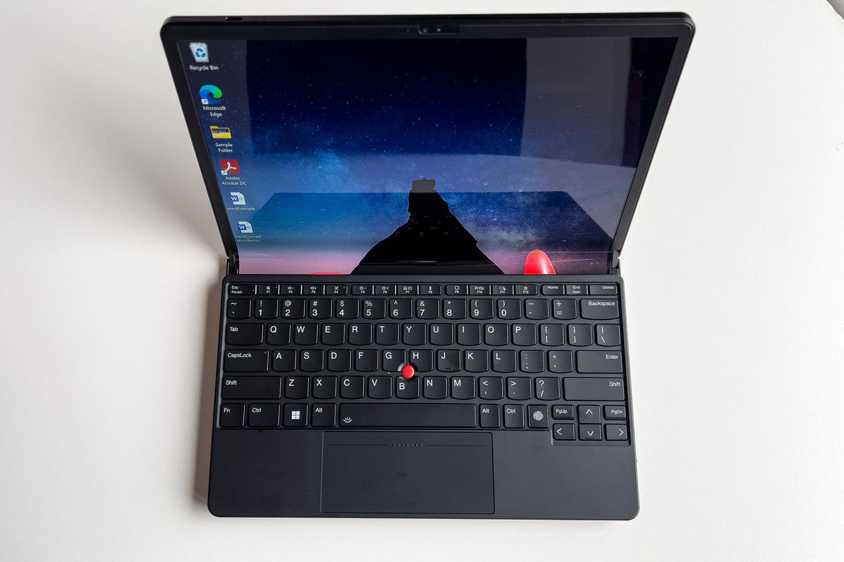 The ThinkPad X1 Fold in laptop mode seen from above. The screen displays a nighttime pastoral scene.